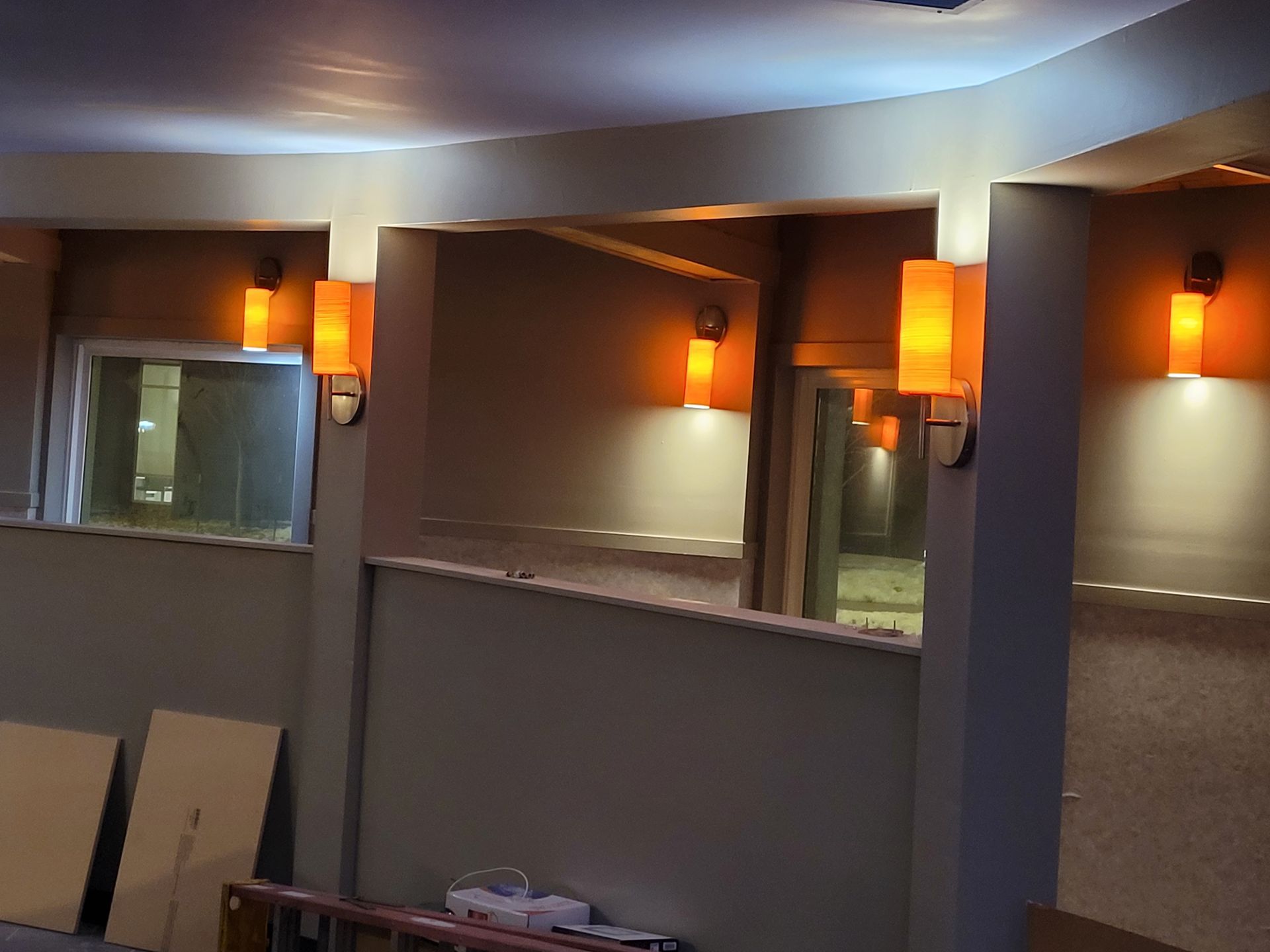 Dim restaurant interior with warm wall sconces, mirrors, and blue accent lighting.