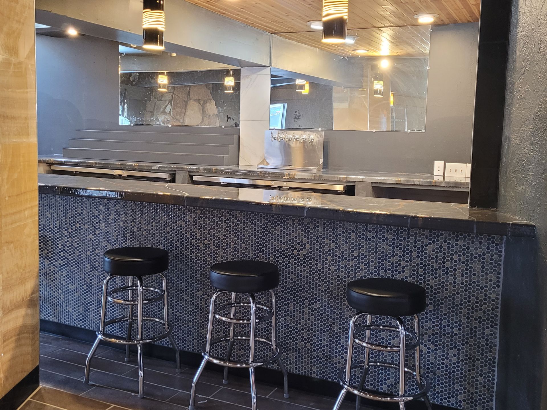 Empty bar with three stools and a mirrored counter in a modern restaurant interior