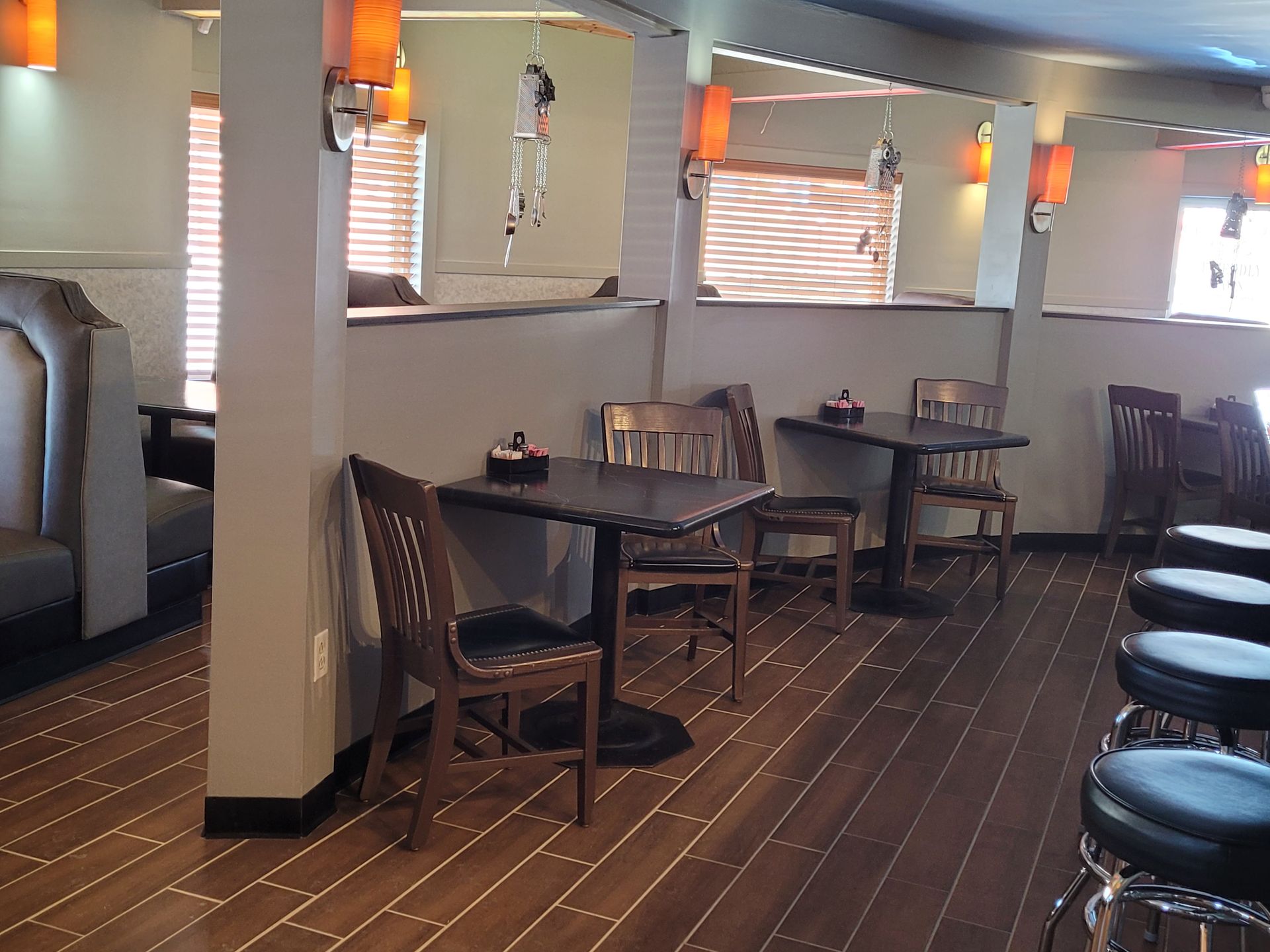 Empty restaurant dining area with wooden tables, chairs, and striped carpet under soft wall lighting