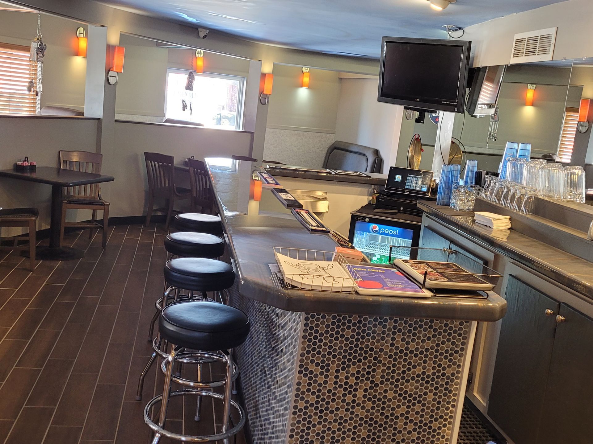 Empty modern bar interior with stools, counter, TVs, and pendant lights