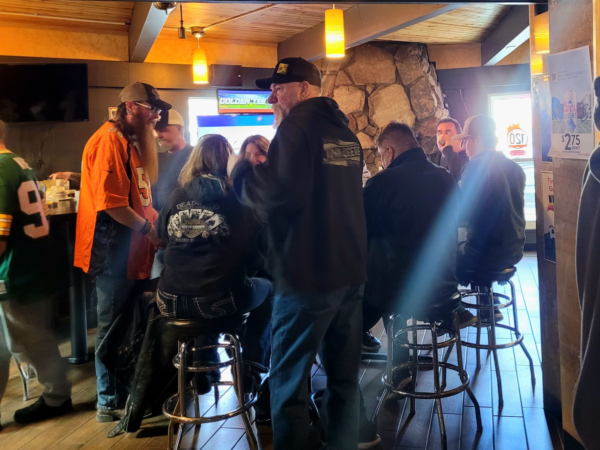 People gathered around stools at a rustic bar with stone walls and warm hanging lights.