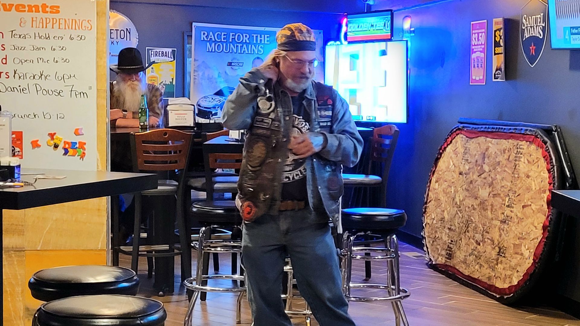 Man performing on a saxophone in a dim bar with neon lights and stools nearby