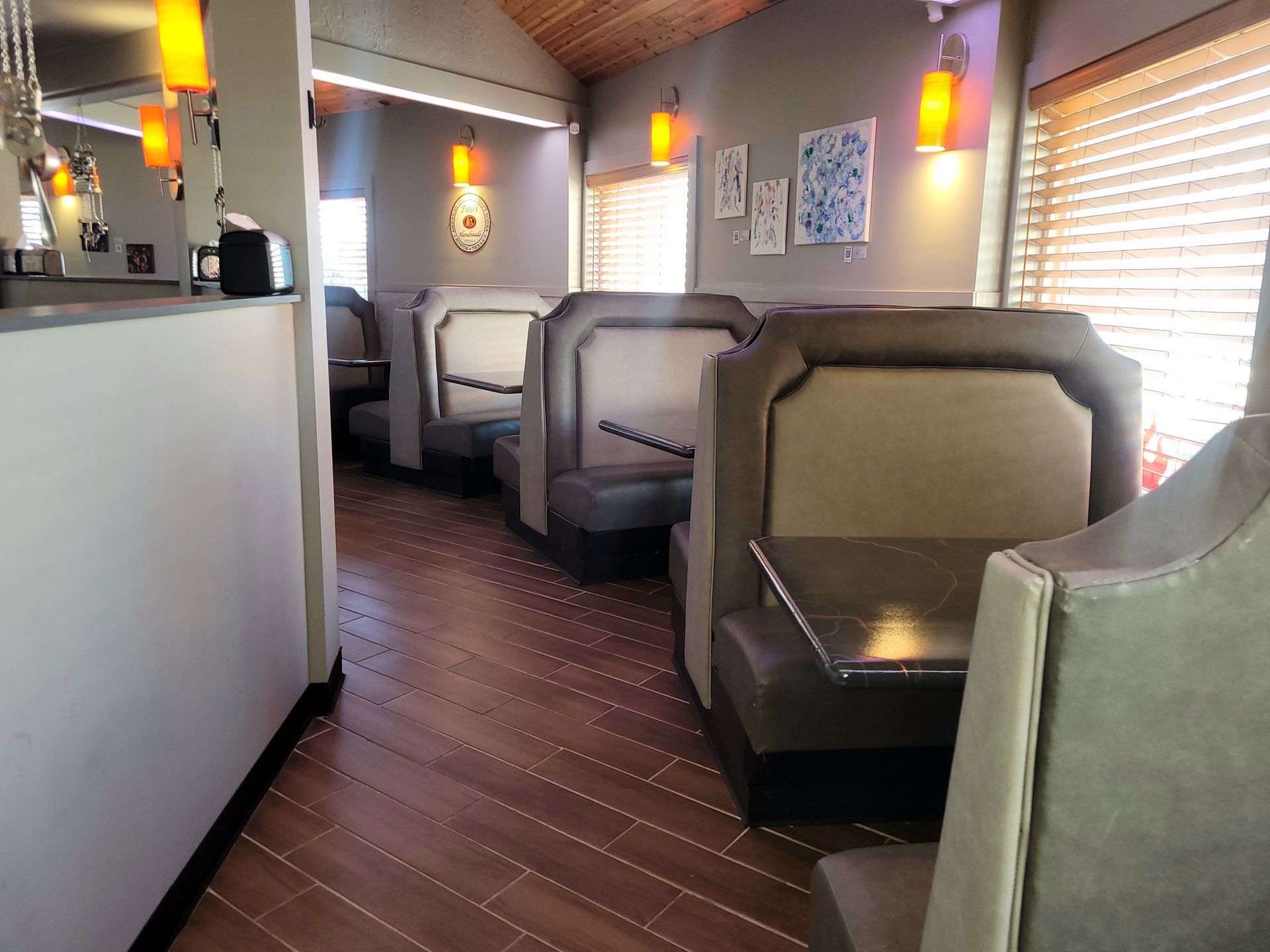 Modern restaurant booth seating along a windowed wall with soft lighting and dark wood floors