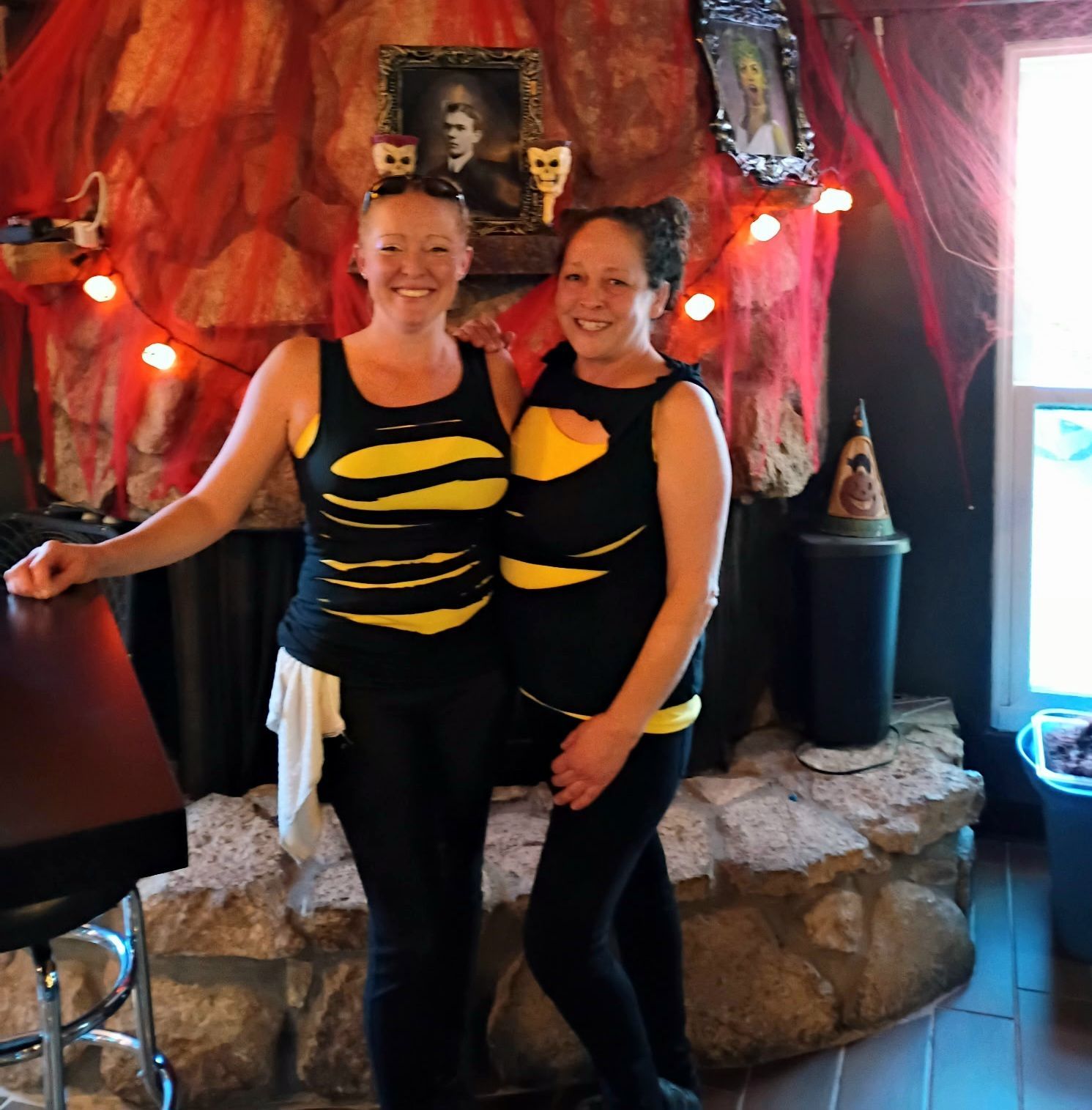 Two people in black and yellow striped outfits posing together in a festive decorated room.