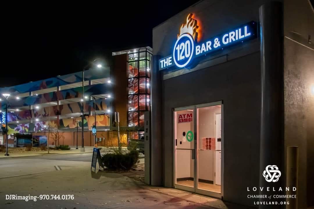 Night view of a restaurant entrance, The 120 Bar & Grill, with neon sign and lit doorway