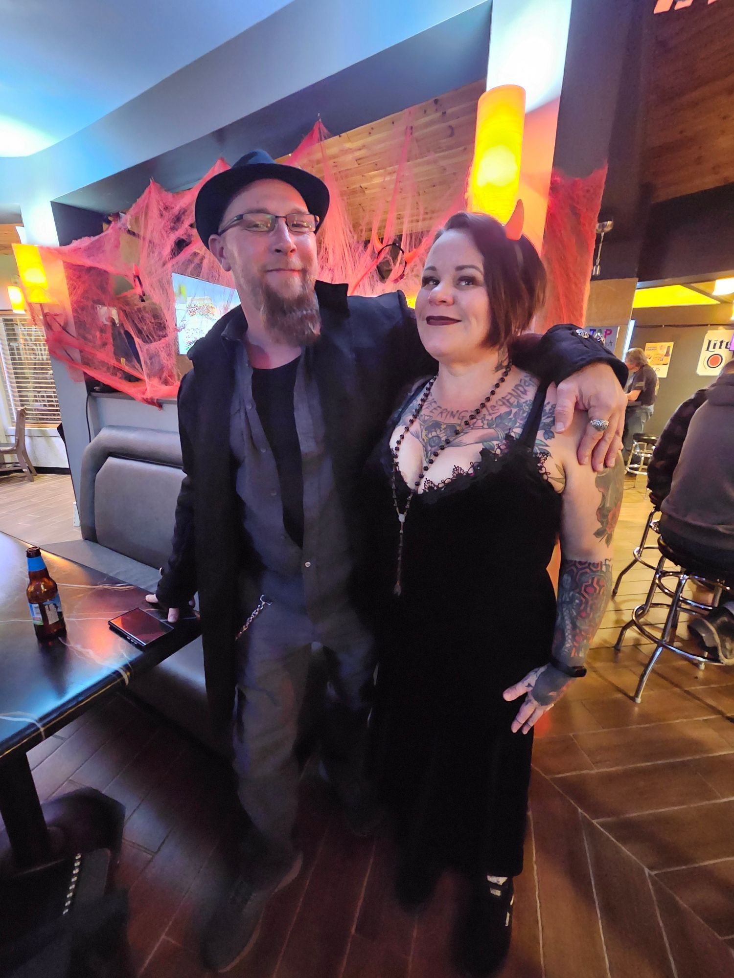 Two adults standing arm-in-arm in a dimly lit lounge with neon wall lights