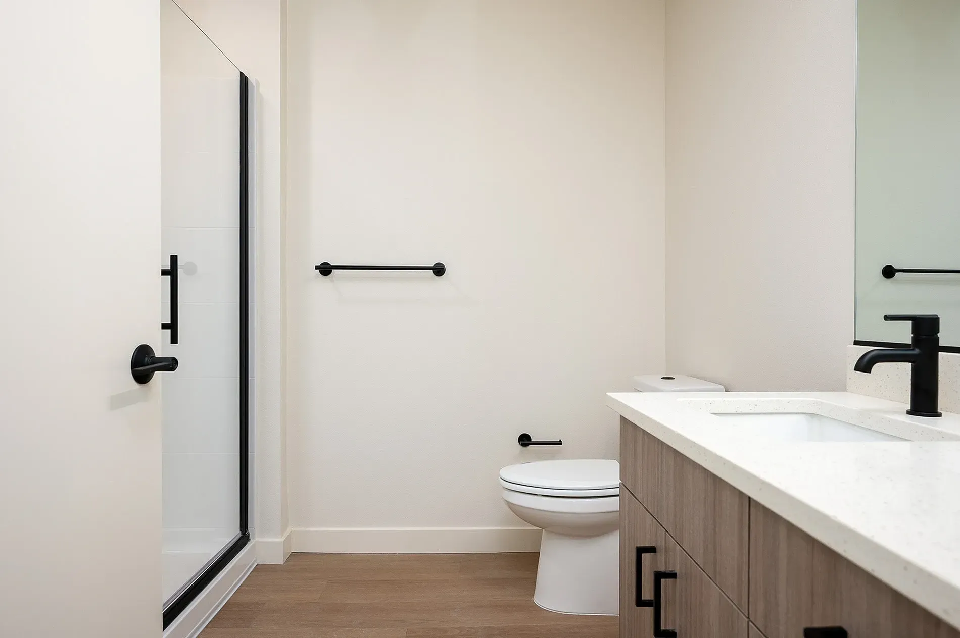 Modern bathroom with a walk-in shower, toilet, and vanity with a sink and black faucet.
