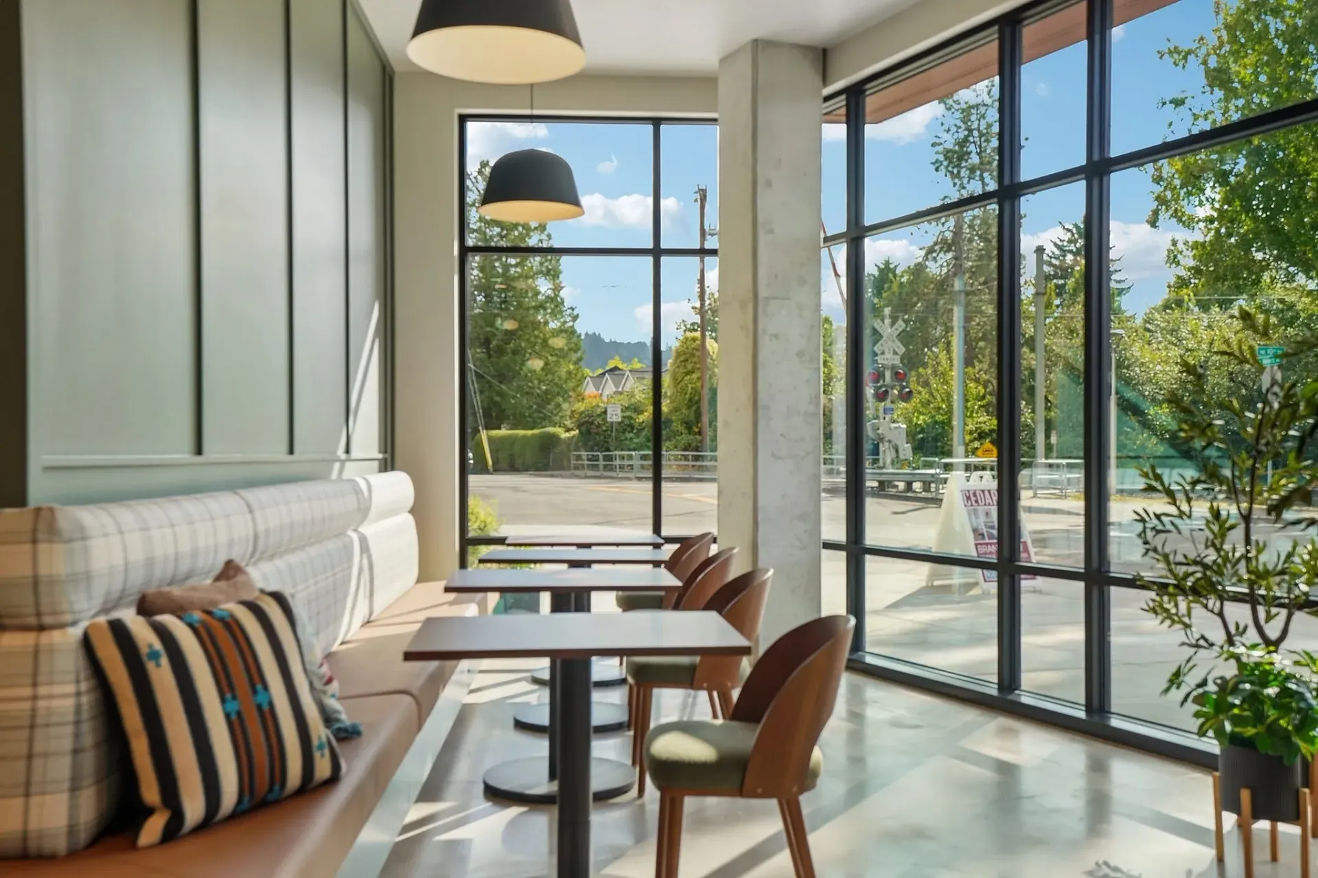 Stylish lounge area with comfortable seating and large windows overlooking a tree-lined street.