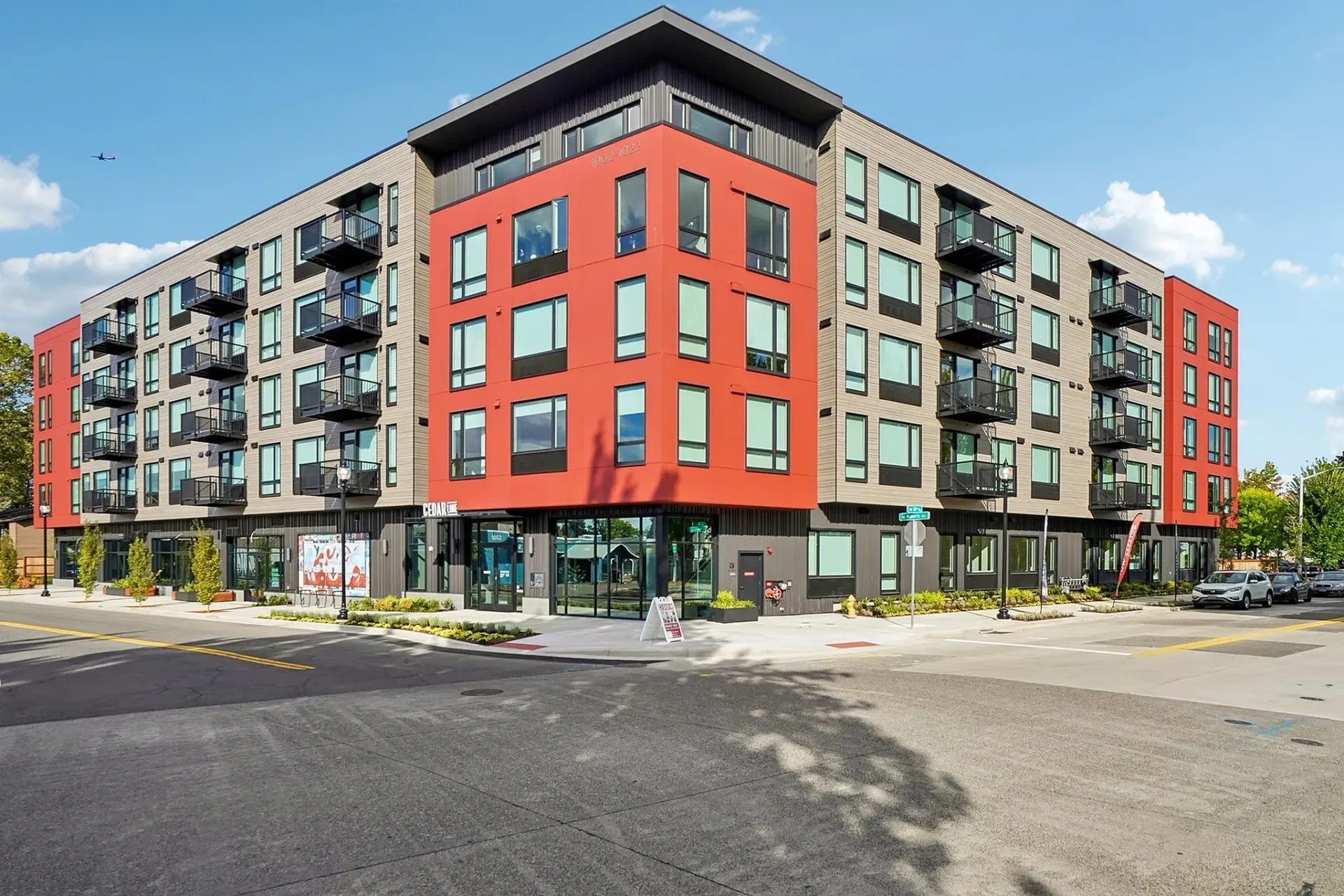 Exterior view of a modern apartment building with red and gray facade and balconies.