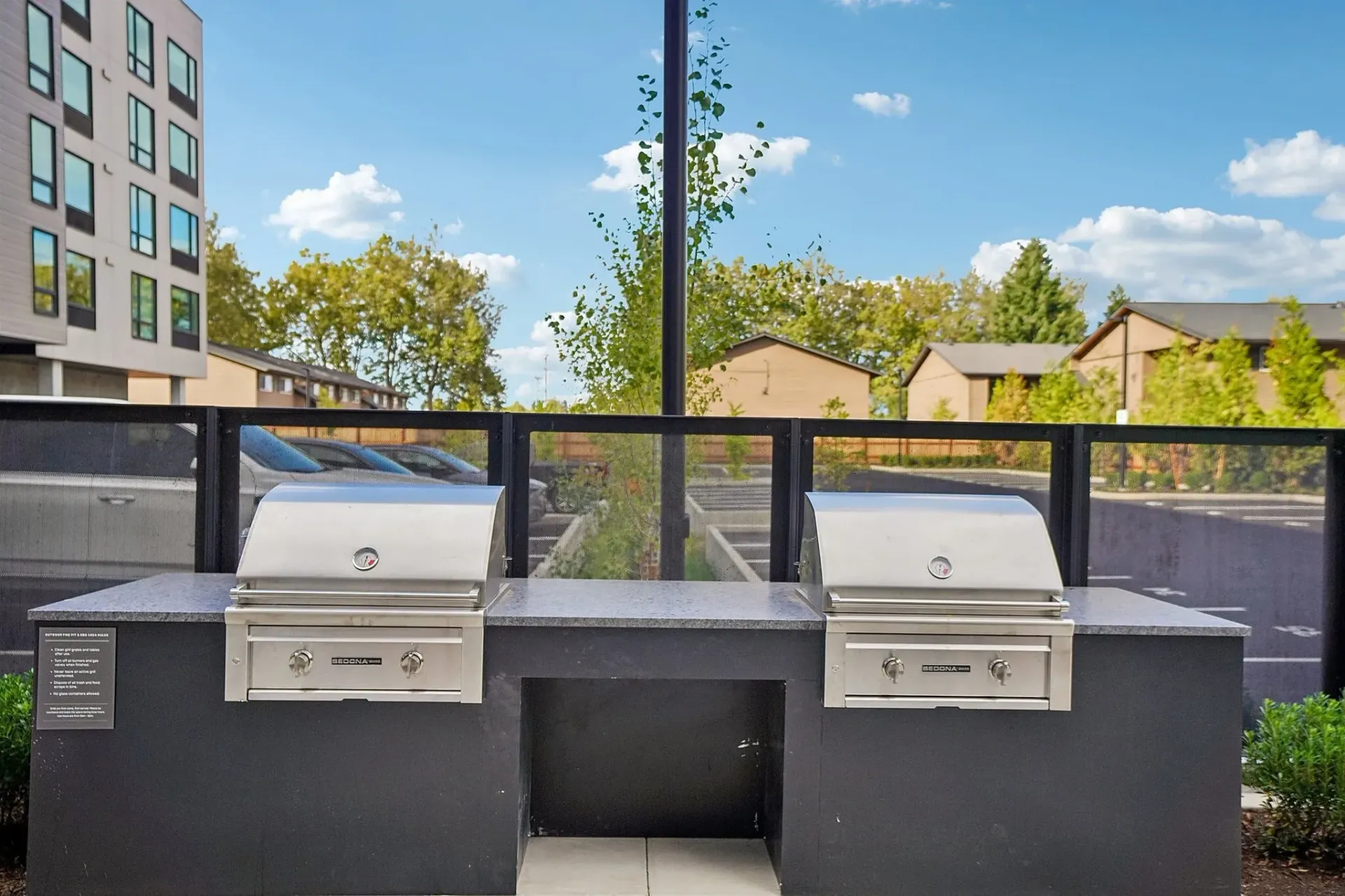 Two stainless steel grills on a stone countertop in an outdoor communal area.