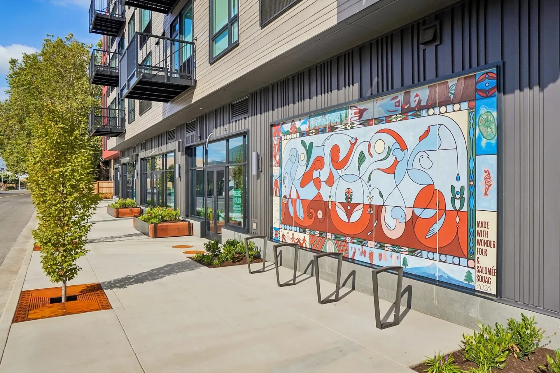 Exterior view of a multifamily building with a colorful mural and bike racks.