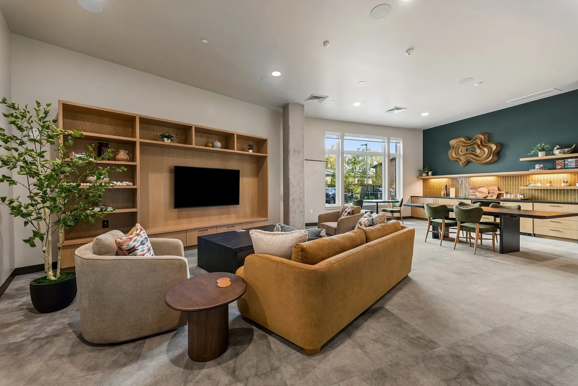 Comfortable seating area with couches and chairs, communal table with chairs, and kitchen counter with stools.