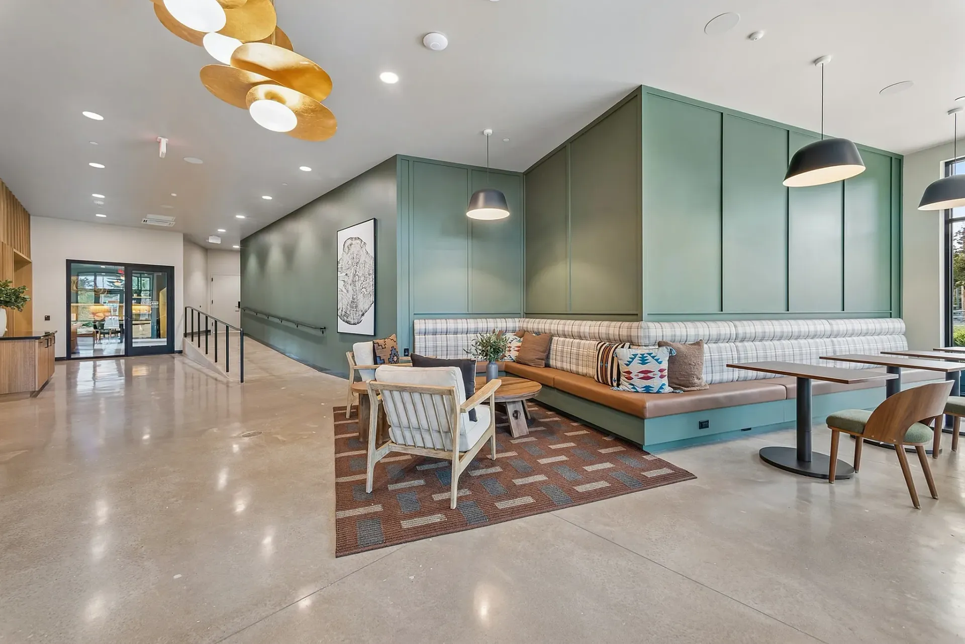 Interior common area lounge with green wall, banquette seating, and modern light fixture.