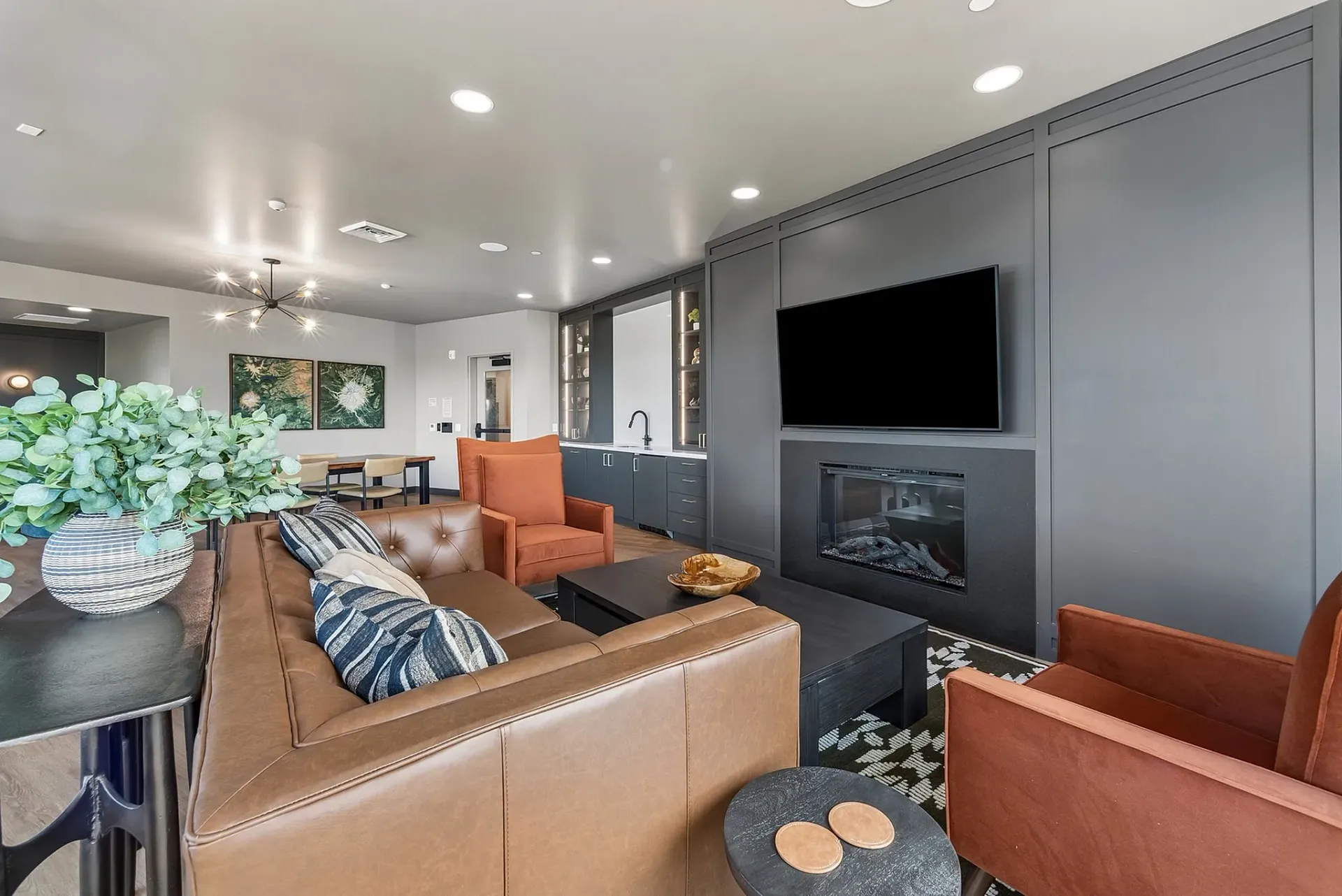 Modern lounge area with a leather sectional, fireplace, TV, and bar area.