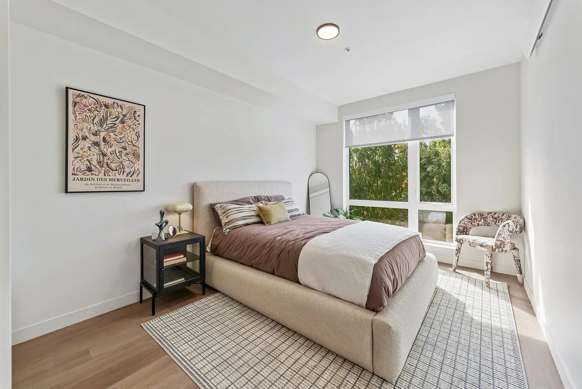 Bedroom with a queen-size bed, nightstand, and a large window.