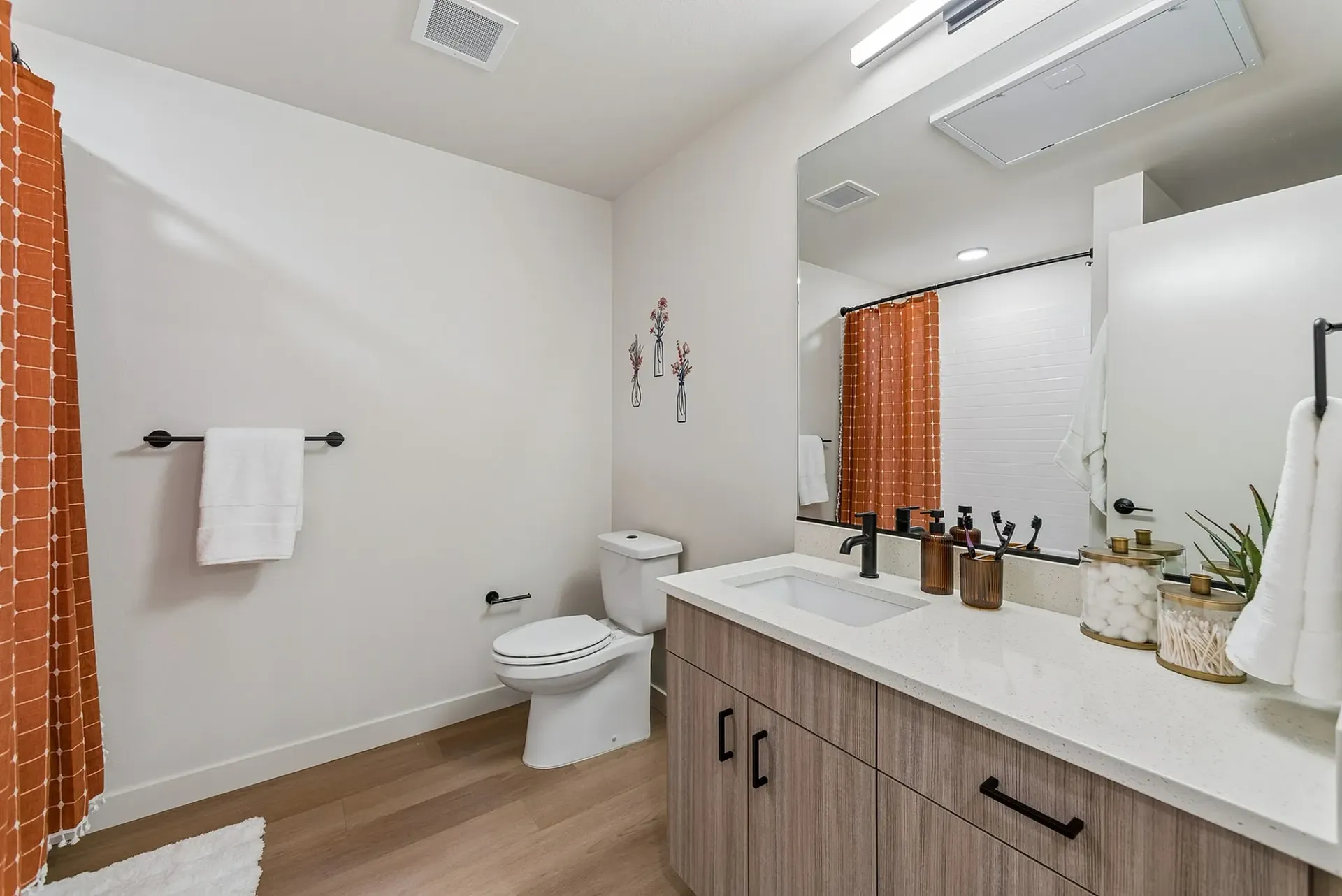 Modern bathroom with a wooden vanity, white countertop, and a sink.