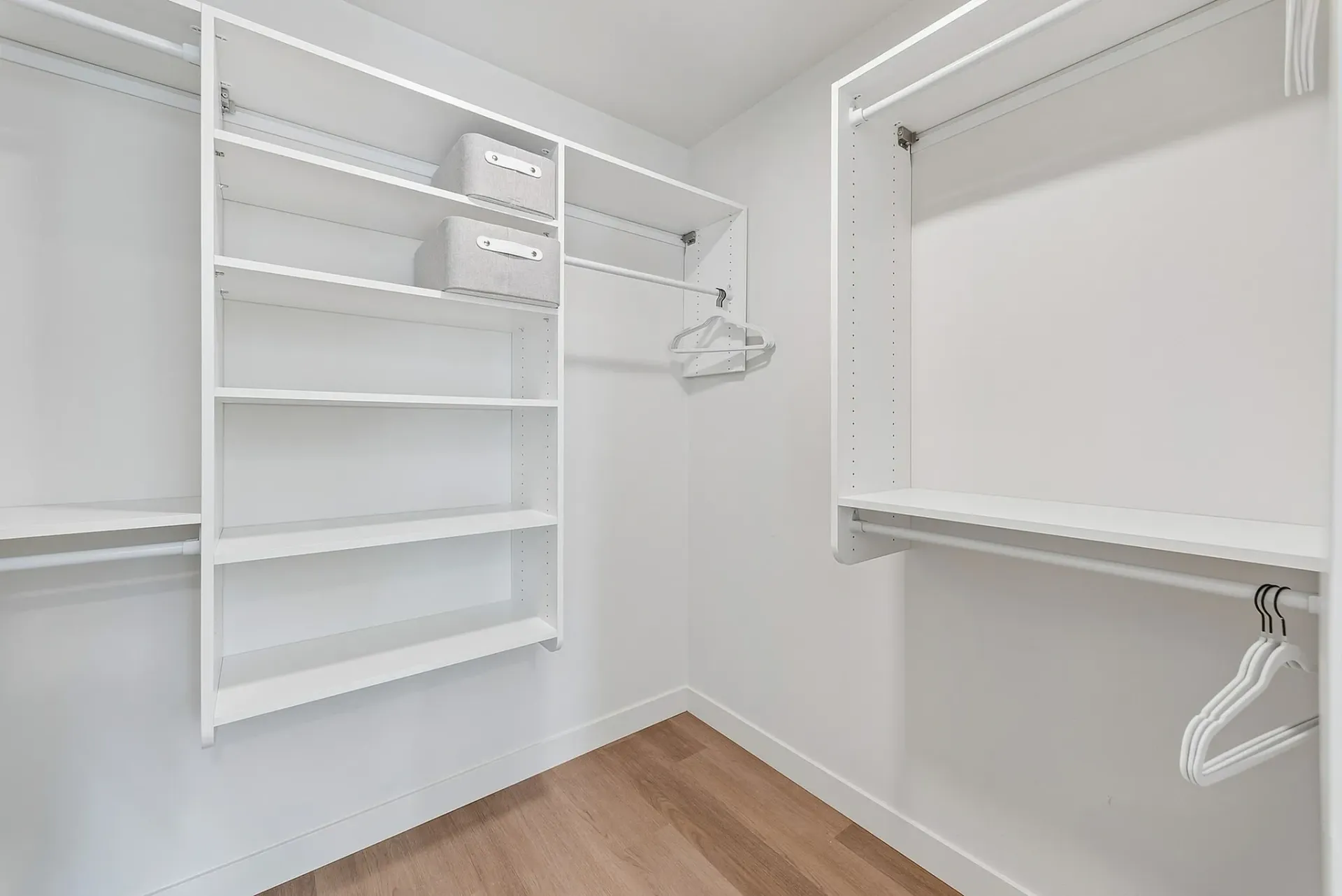 Empty walk-in closet with white shelves and hanging rods.