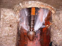 Worker drilling into rock with water spray at a tunnel entrance