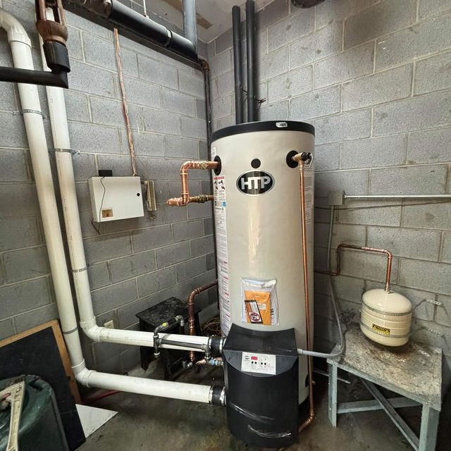 Basement utility room with a tall water heater, pipes, and cinder block walls