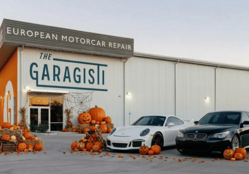 The Garagisti shop decorated with pumpkins and Halloween décor, featuring a Porsche and BMW vehicle.