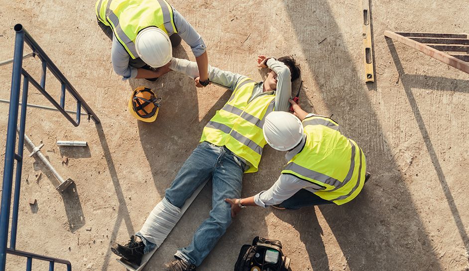 Un groupe d'ouvriers du bâtiment aident un homme qui est allongé sur le sol.