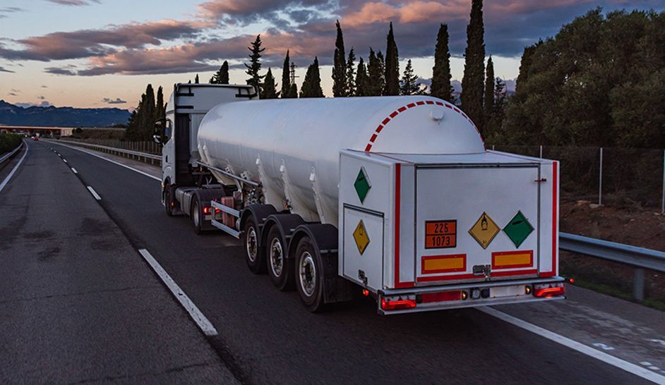 Un camion-citerne roule sur une autoroute au coucher du soleil.