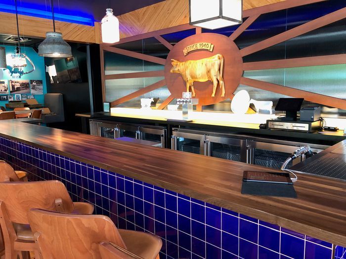 A bar in a restaurant with a cow on the wall