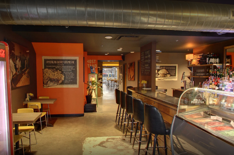 A restaurant with tables and chairs and a bar.
