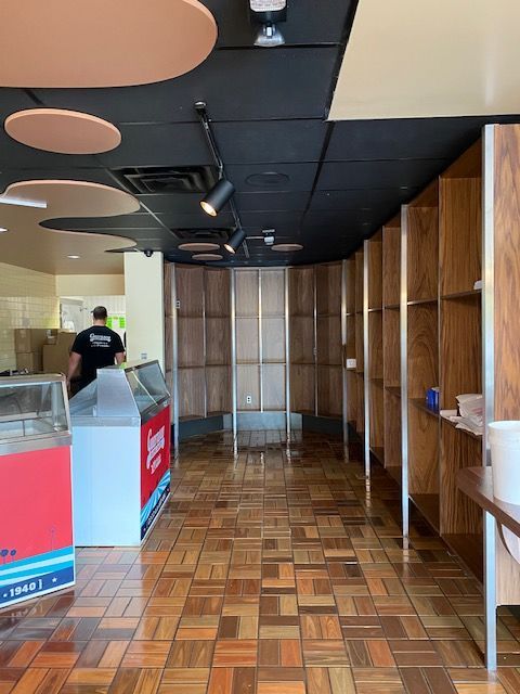 An empty restaurant with a wooden floor and shelves.