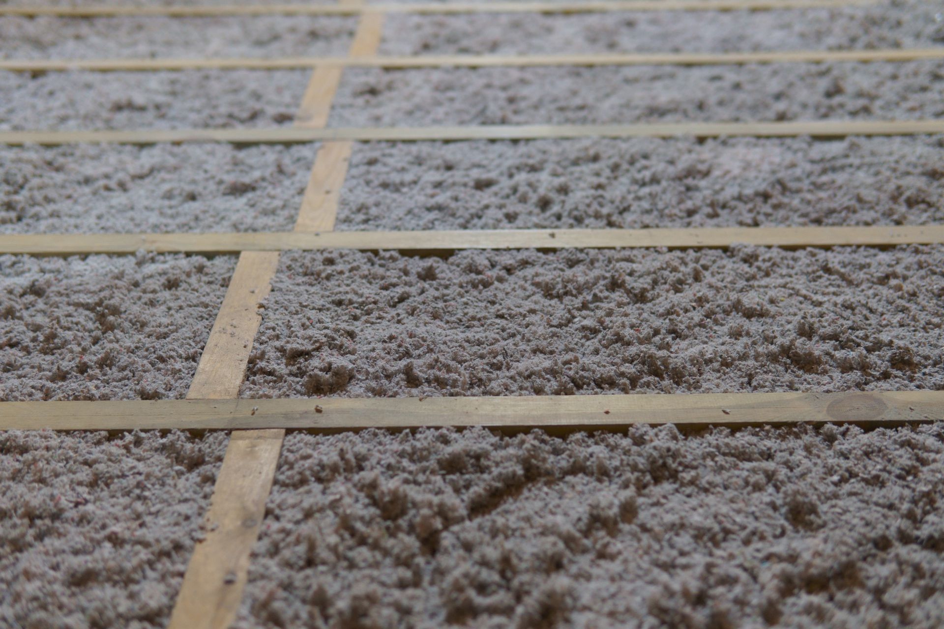 Loose gray insulation with evenly spaced tan strips.