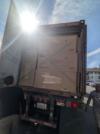Inside a moving truck: stacked furniture, boxes, trash cans, and a bicycle near the open rear door.