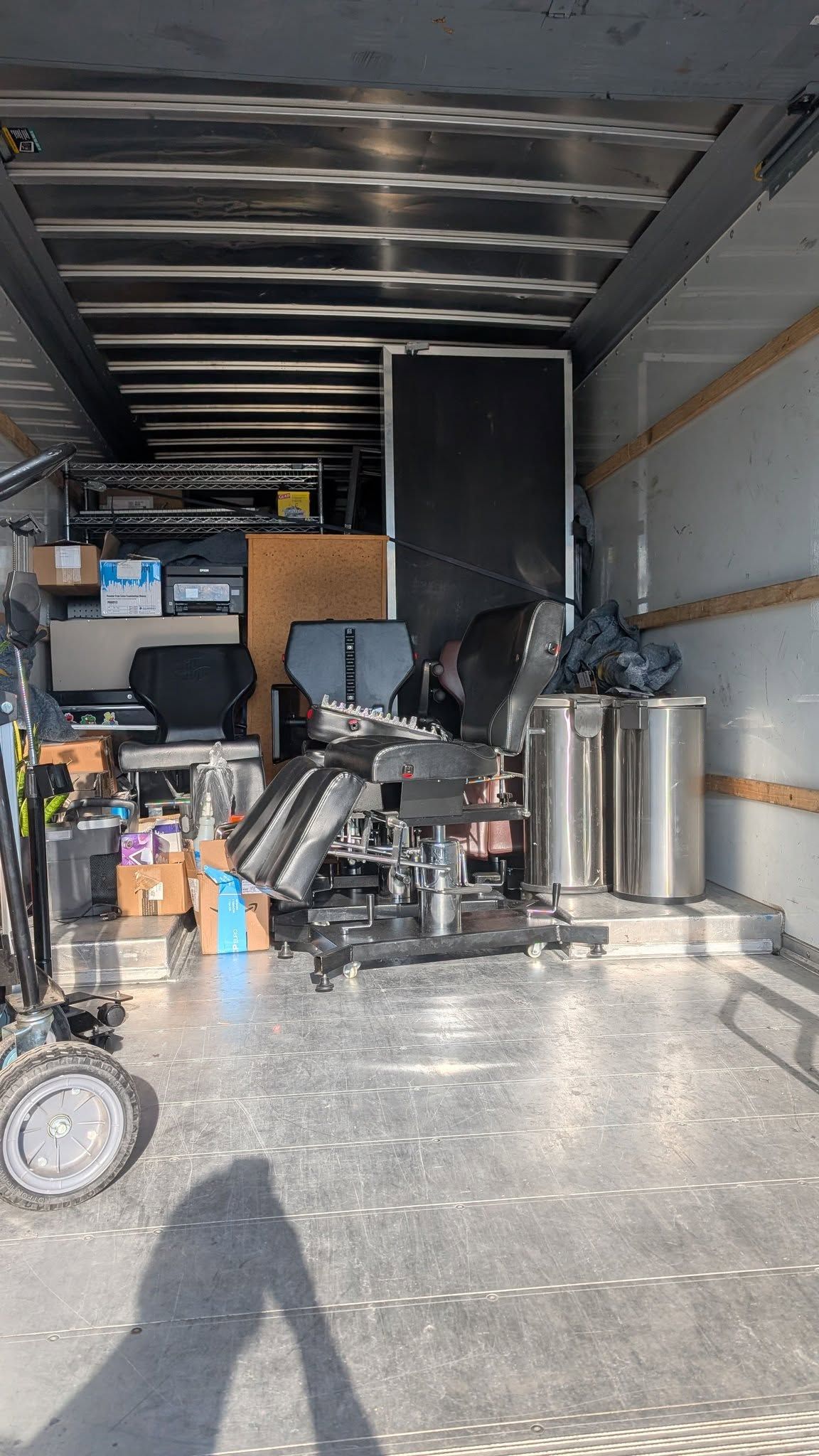 Packed moving truck interior with stacked furniture, bins, and bags filling the cargo space