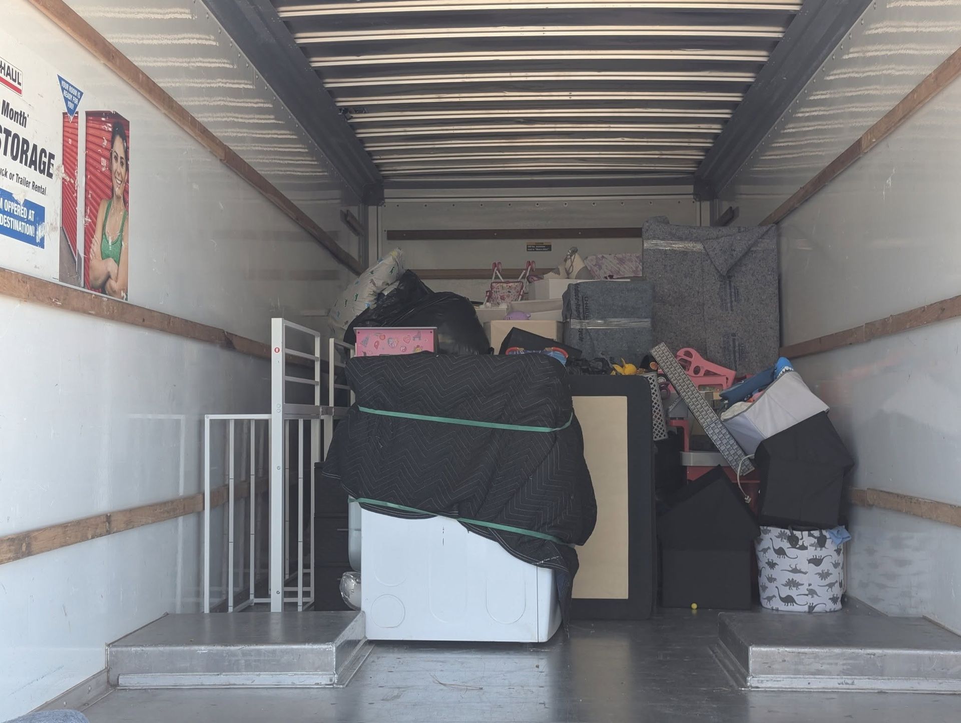 Packed moving truck interior with boxes, furniture, and covered items secured inside
