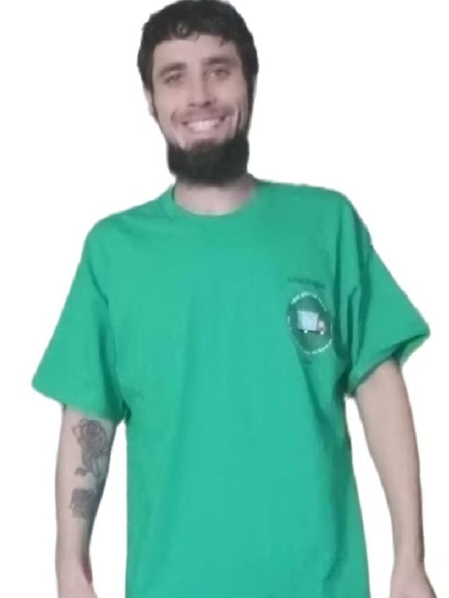 Smiling person in a green T-shirt standing against a white background.