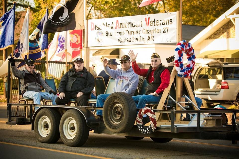 Veterans on a decorated parade float waving American flags and a Vietnam Veterans banner