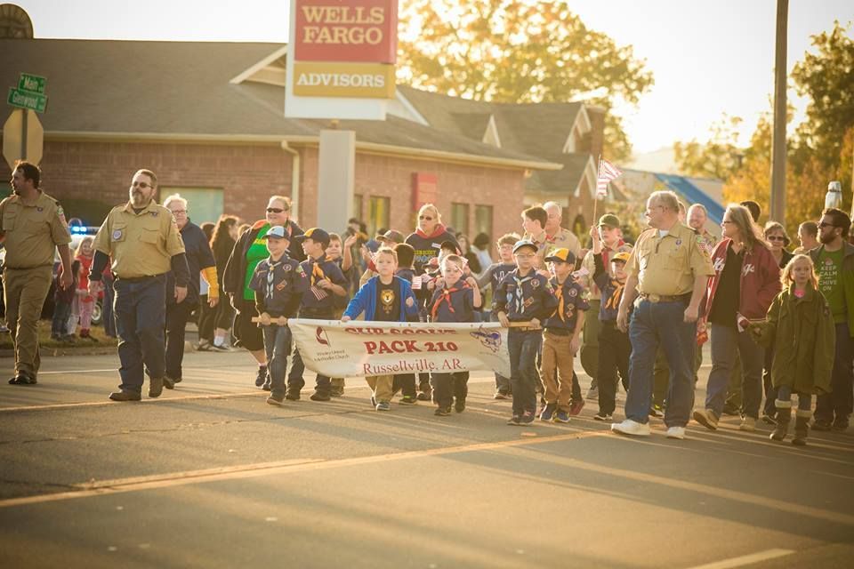 Crowd holding a banner marching down a sunlit street past a Wells Fargo building
