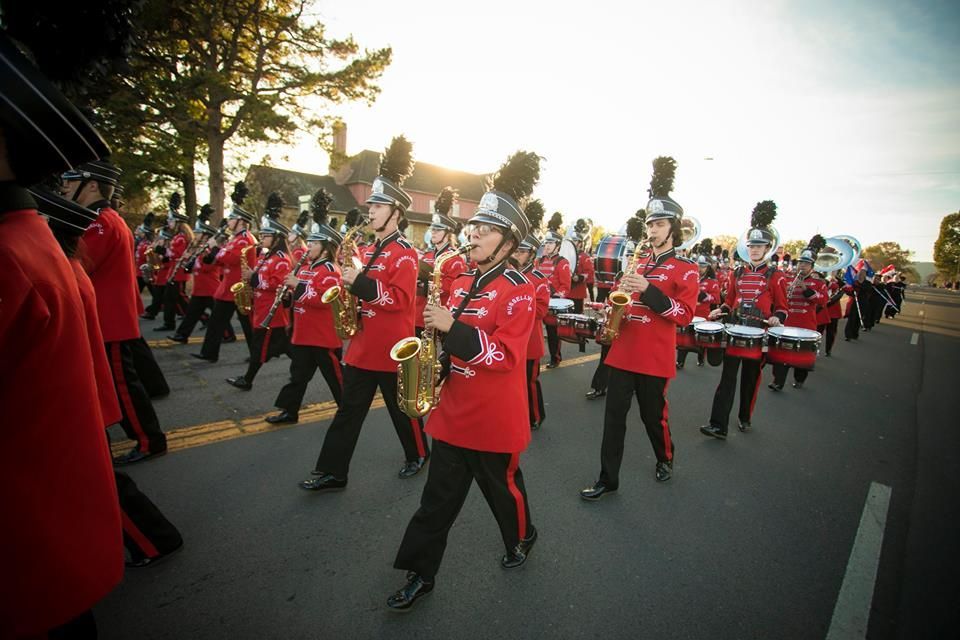 Marching band in red uniforms performing on a street during a parade