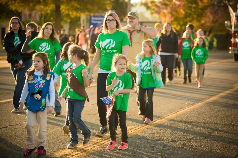 People in green shirts walking together outdoors on a sunny path during a community event