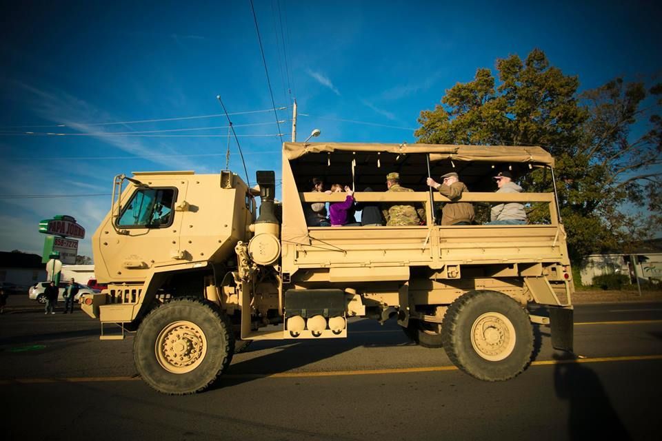 Military truck carrying passengers on a road at sunset