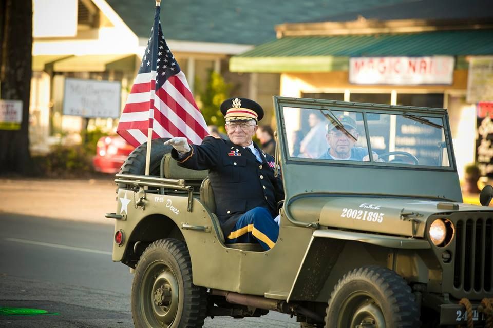 Veteran in military jeep with American flag at a nighttime parade