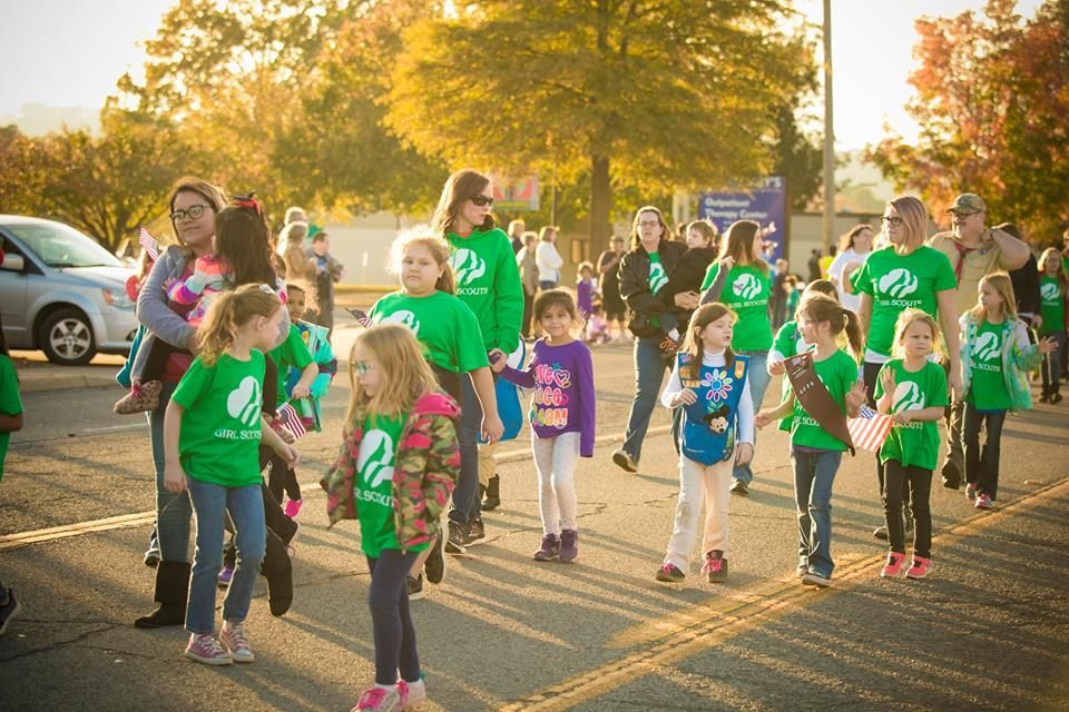 People in green shirts walking together outdoors in warm sunset light, some holding hands.