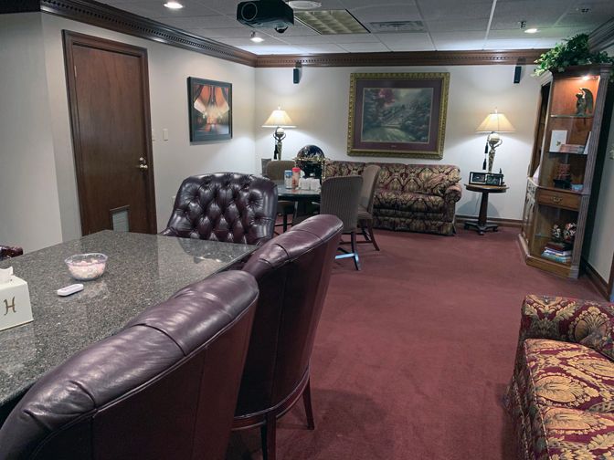 Cozy waiting room with leather chairs, sofa, lamps, framed art, and maroon carpet.