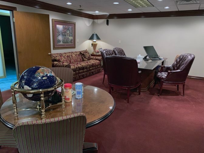 Office lounge with sofa, chairs, table, and globe on a round glass table.