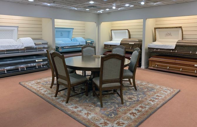 Furniture showroom with beds displayed around a dining table on a rug