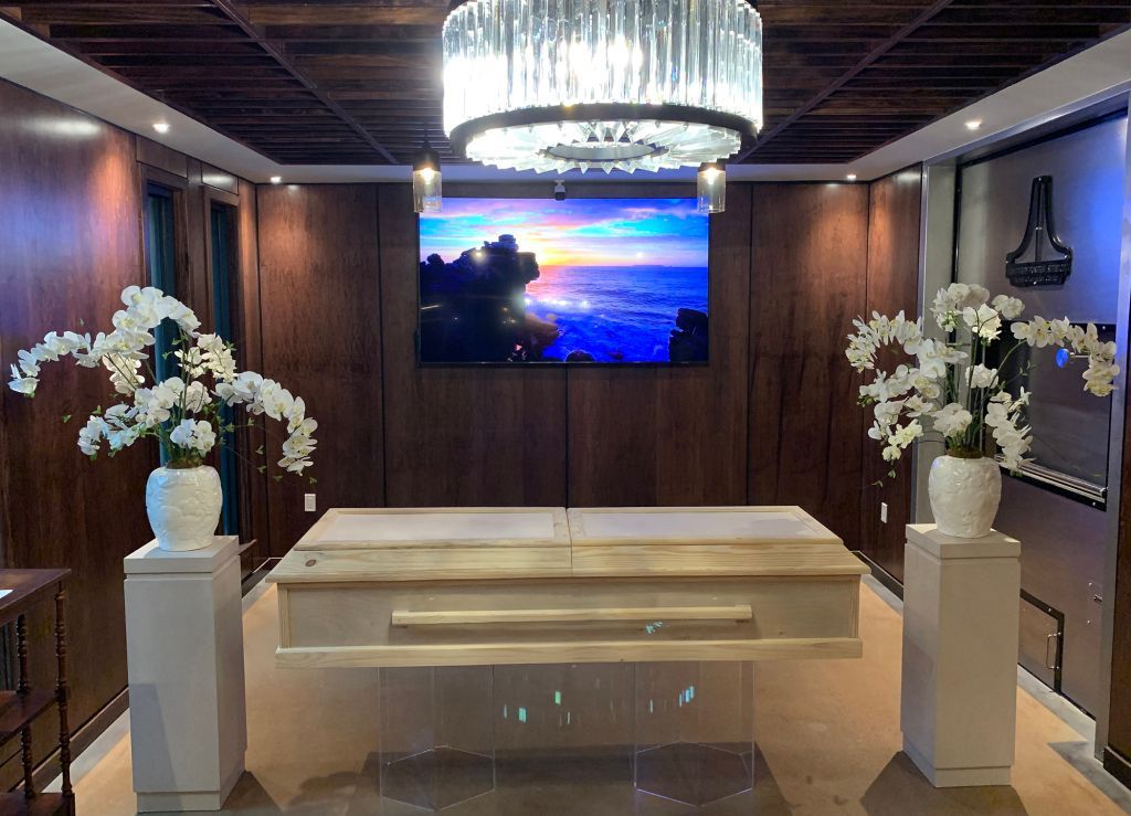 Elegant wedding altar with white flowers, candles, wooden backdrop, and a central screen above a white platform.