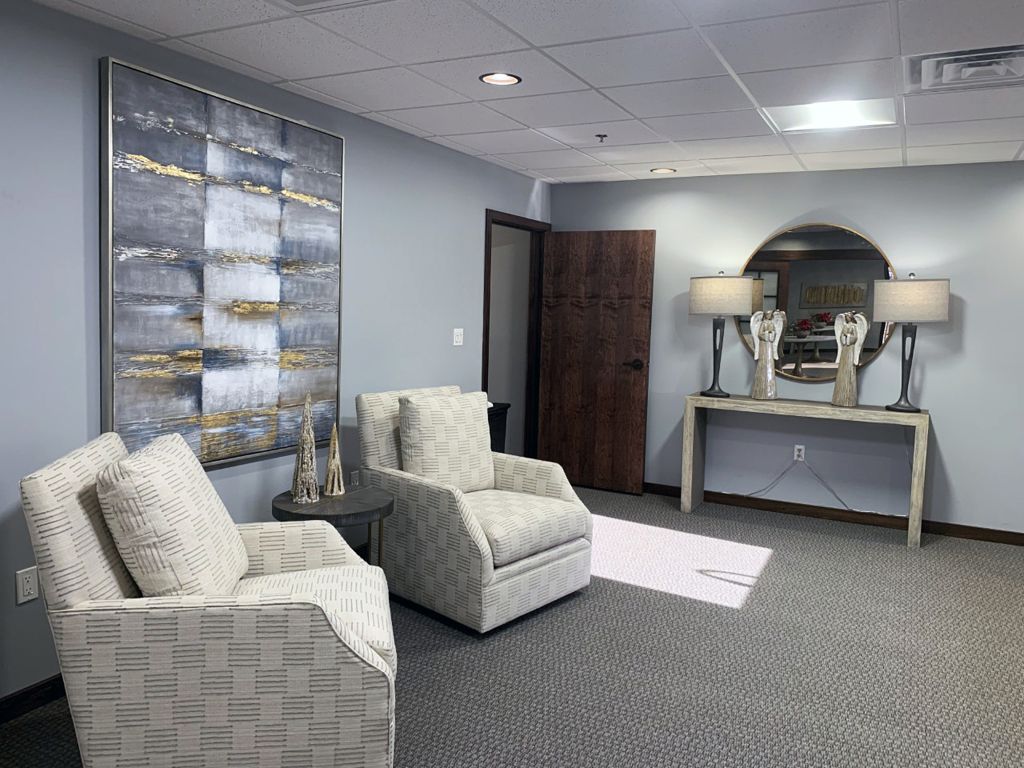 Modern waiting room with gray chairs, abstract wall art, and a console table with lamps.