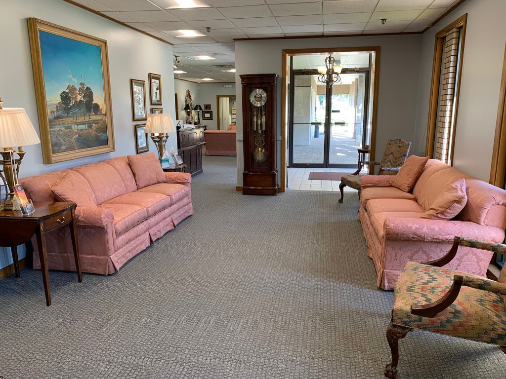 Elegant lobby with pink sofas, framed art, lamps, and a glass entrance doorway