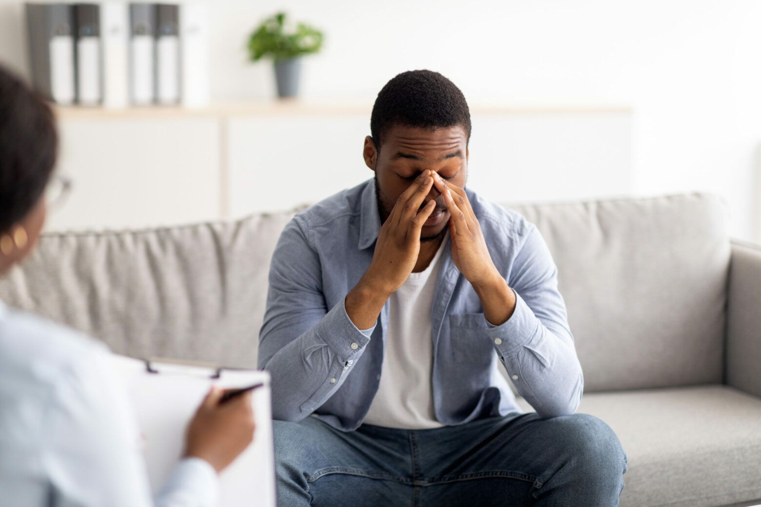 Man sitting on a couch, holding his face in his hands during a counseling session