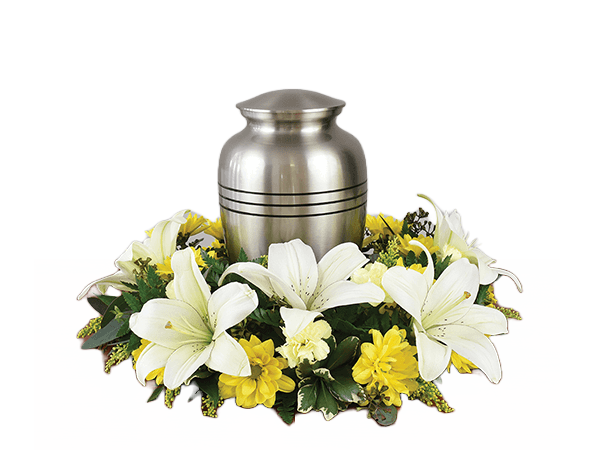 Silver cremation urn surrounded by white lilies and yellow flowers