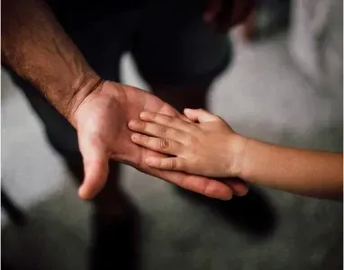 A child's hand resting on an adult's hand, symbolizing comfort and support during grief.
